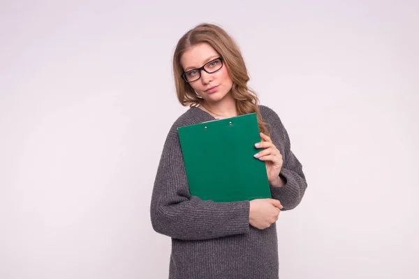 Bildung, Studentin und Volkskonzept - attraktive Frau mit weißem Hintergrund im grauen Pullover hält Papiermappe in der Hand — Stockfoto