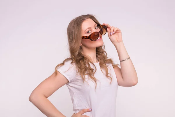 Modische junge Frau mit T-Shirt und Sonnenbrille vor weißem Hintergrund — Stockfoto