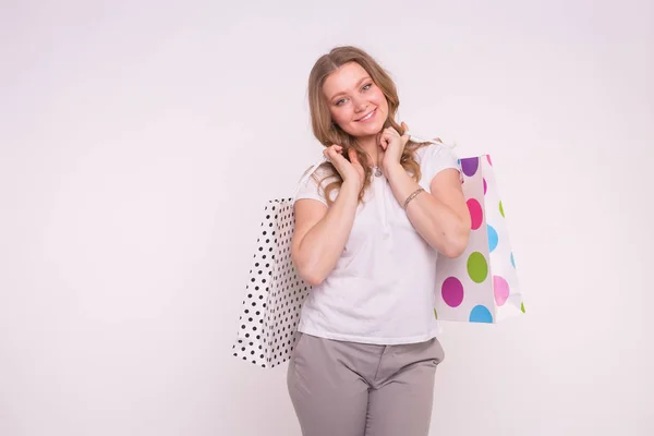 Mensen, verkoop en consumentisme concept - aantrekkelijke jonge blonde vrouw met winkelen veelkleurige zakken over witte achtergrond met kopie ruimte — Stockfoto