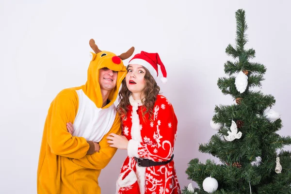 Vacances, humour, concept de personnes - Heureuse jeune femme au chapeau de Père Noël et homme en costume de carnaval de cerf — Photo