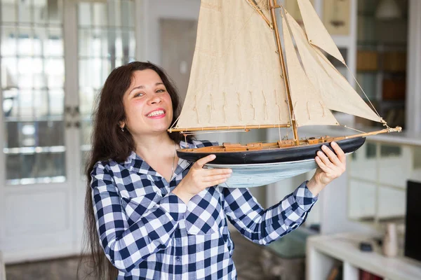 Hobby, verzamelen, schip en mensen concept - jonge vrouw bedrijf lay-out van een zeilboot — Stockfoto