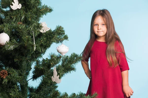Μικρό κορίτσι με το χριστουγεννιάτικο δέντρο σε μπλε φόντο — Φωτογραφία Αρχείου