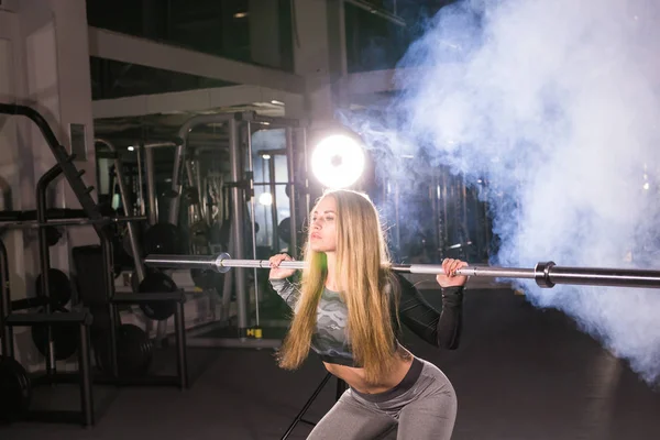 Sport, Fitness, Trainings- und Glückskonzept - sportliche Frau mit Langhantel im Fitnessstudio — Stockfoto