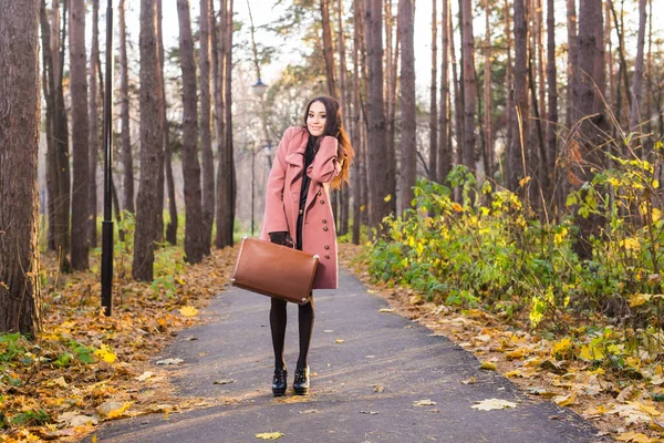 Otoño, naturaleza y concepto de personas - Retrato de una hermosa mujer sonriente en abrigo beige con bolsa marrón — Foto de Stock