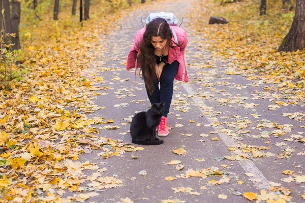 Menschen, Haustierbesitzer und Saisonkonzept - junge Frau und eine schwarze Katze im Herbstpark — Stockfoto