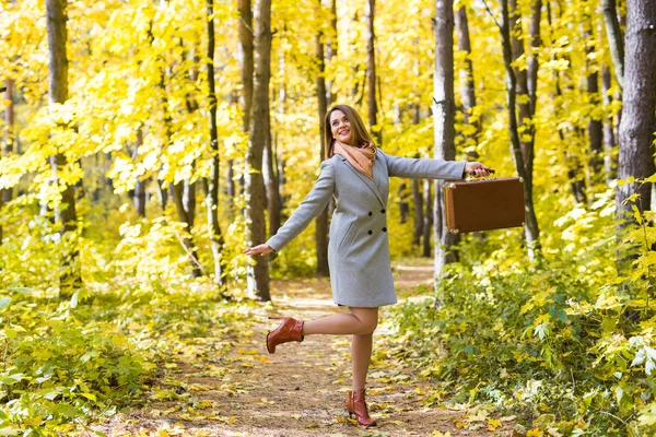 Season, nature and people concept - woman in autumn park posing with suitcase — Stock Photo, Image