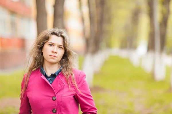 Podzim, příroda a lidé koncept - Mladá krásná žena v růžový kabát, stojící v podzimním parku s kopií prostor — Stock fotografie