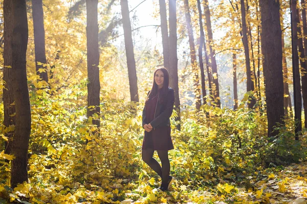 Herfst, de natuur en de mensen concept - jonge brunette vrouw in leren jas wandelen in het park — Stockfoto