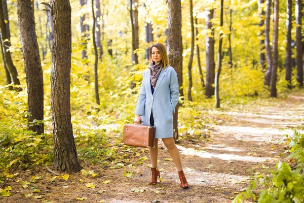 Fall, season and people concept - woman in autumn park walkng with suitcase — Stock Photo, Image