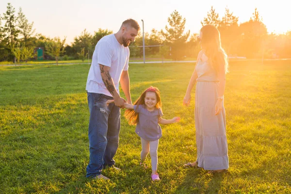 Amistosa familia caminando en el parque y divertirse juntos — Foto de Stock