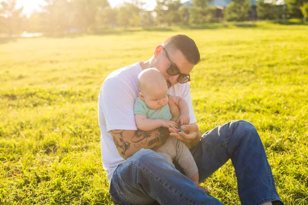 Heureux père tenant bébé fils sur la nature. Concept de famille heureuse, fête des pères et des enfants . — Photo