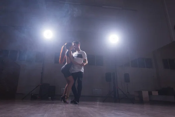 Young couple dancing latin music: Bachata, merengue, salsa. Two elegance pose on white room.