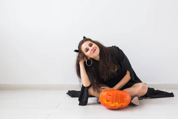 Leuke gotische vrouw in halloween stijl kleding met pompoen in handen — Stockfoto