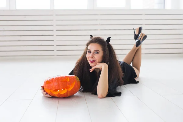 Милая готическая женщина в одежде в стиле Хэллоуина с тыквой в руках — стоковое фото