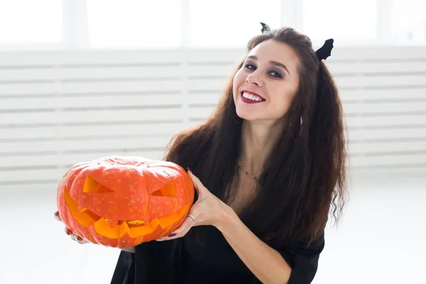 Niedliche gotische Frau in Halloween-Kleidung mit Kürbis in den Händen — Stockfoto