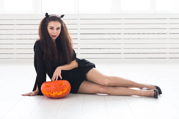 Joyeux gothique jeune femme en costume de sorcière halloween souriant sur fond de chambre blanche — Photo