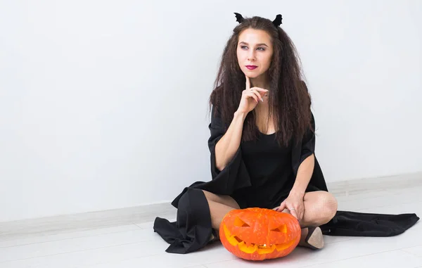 Joyeux gothique jeune femme en costume de sorcière halloween souriant sur fond de chambre blanche — Photo