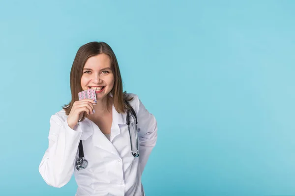 Νεαρή γυναίκα γιατρό γευσιγνωσία πακέτο των χαπιών σε μπλε φόντο με αντίγραφο χώρου — Φωτογραφία Αρχείου