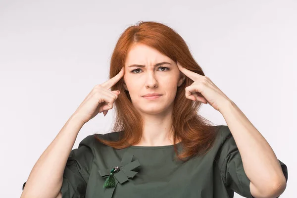 Mulher ruiva estressada tocando templos e pensando muito no fundo branco. Conceito de estresse ou dor de cabeça . — Fotografia de Stock