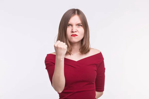 Retrato de uma jovem irritada mostrando um punho no fundo branco — Fotografia de Stock