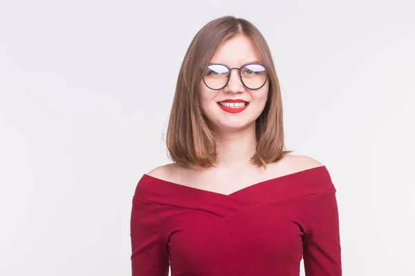Koncept módní a lidé - portrét mladé usmívající se žena v brýlích v červené košili na bílém pozadí — Stock fotografie