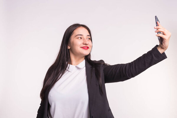 Technology, smartphone and people concept - Happy young asian woman making selfie over white background