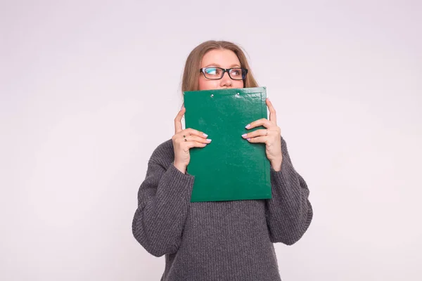 Smart junge blonde Frau mit Brille versteckt sich hinter grünem Papierordner. — Stockfoto