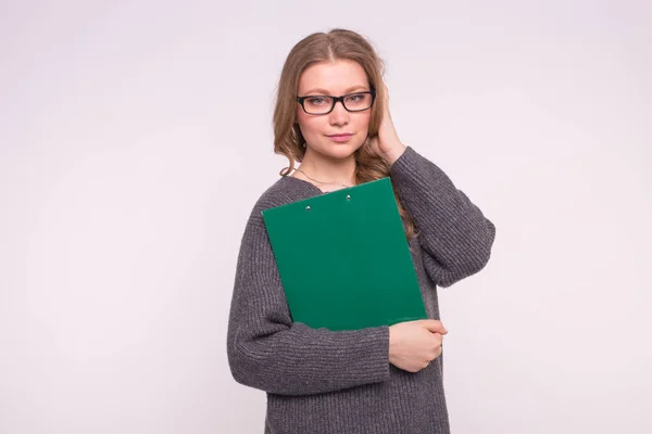 Bildung, Studentin und Volkskonzept - attraktive Frau mit weißem Hintergrund im grauen Pullover hält Papiermappe in der Hand — Stockfoto