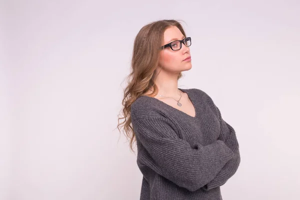 Concept d'émotions et de personnes - Jeune femme sur fond blanc avec espace de copie dans un pull à tricoter gris se serrant dans ses bras en regardant la caméra — Photo
