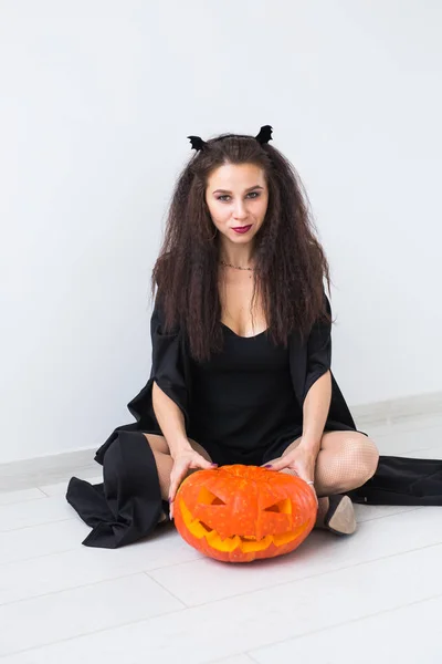 Glimlachend brunette vrouw in halloween make-up poseren met gebeeldhouwde pompoen — Stockfoto