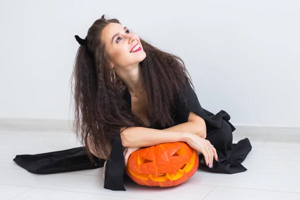 Halloween en maskerade concept - mooie jonge vrouw poseren met pompoen Jack-o-lantaarn. — Stockfoto