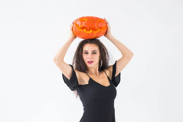 Mulher morena sorridente em maquiagem halloween posando com abóbora esculpida — Fotografia de Stock