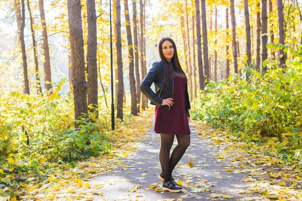 Herbst, Jahreszeit und Menschen-Konzept - junge brünette Frau steht im Herbstpark — Stockfoto