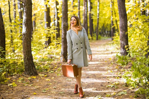 Herbst, Jahreszeit und Menschen-Konzept - Frau im rosafarbenen Mantel mit braunem Etui steht im Herbstpark vor dem Hintergrund der Natur — Stockfoto