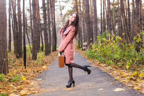 Pessoas, conceito de temporada e moda - Mulher morena com mala retro no parque de outono . — Fotografia de Stock