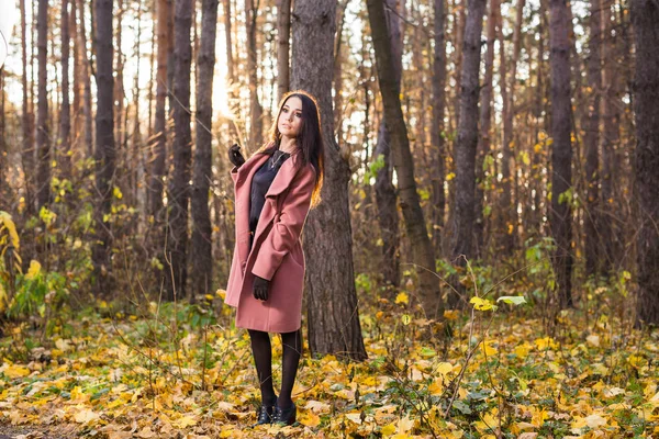 Young stylish brunette woman walking in autumn park — Stock Photo, Image