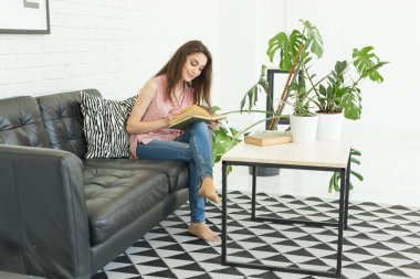 İnsanlar, eğitim ve iç kavramı - kanepede oturan ve bir kitap okuma genç öğrenci kadın