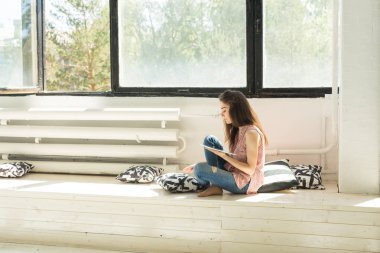 Teknoloji ve insan kavramı - tablet ve yastık ile ahşap eşiğinde oturan genç güzel kadın