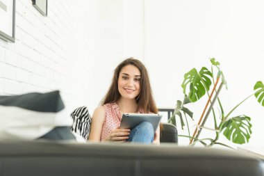 Teknolojileri, insanlar kavramı - kanepe ve tablet izlerken veya net sörf ve gülümseyen üzerinde oturan genç kadın