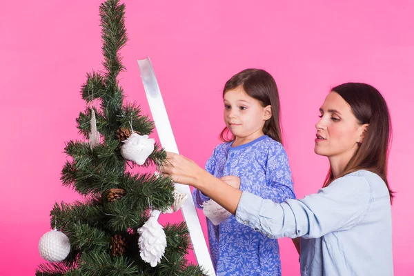Święta, Rodzina i koncepcja Boże Narodzenie - matka i córka dekorowanie choinki na różowym tle — Zdjęcie stockowe