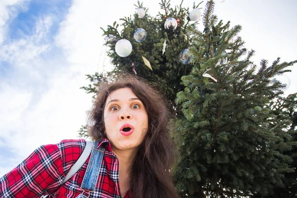 Yılbaşı, bayram, mizah ve insanlar kavramı - sürpriz gösterilen Noel ağacının altında genç mutlu kadın — Stok fotoğraf