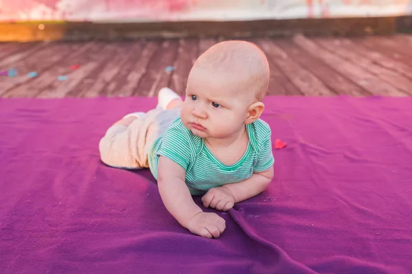 Niño lindo bebé acostado en la manta en el día de verano en la naturaleza. Picnic familiar en un parque . — Foto de Stock