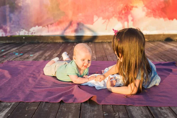 Niño lindo bebé y niña pequeña acostada en manta en el día de verano en la naturaleza. Concepto de hermano y hermana — Foto de Stock