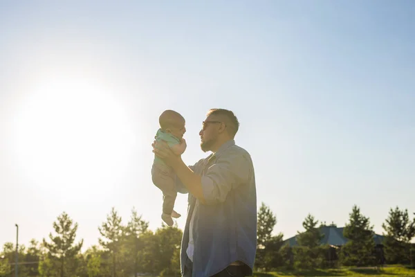 Feliz padre sosteniendo bebé hijo en la naturaleza. Concepto de familia feliz, día del padre y el niño . — Foto de Stock