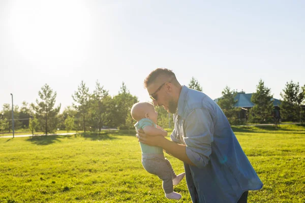 Feliz padre sosteniendo bebé hijo en la naturaleza. Concepto de familia feliz, día del padre y el niño . — Foto de Stock