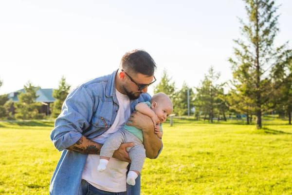 Feliz padre sosteniendo bebé hijo en la naturaleza. Concepto de familia feliz, día del padre y el niño . — Foto de Stock