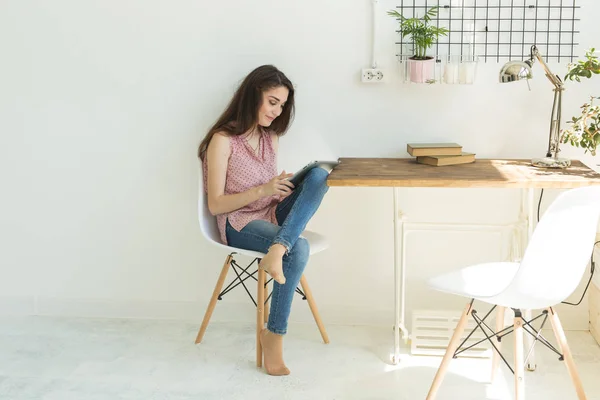 Les gens, concept intérieur et de loisirs - heureuse jeune femme avec tablette numérique assis sur une chaise dans la salle de lumière — Photo