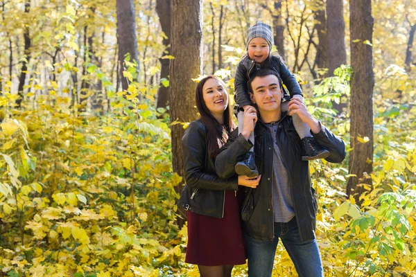 Family, fall, people concept - mixed race young family walking in park on in autumn day