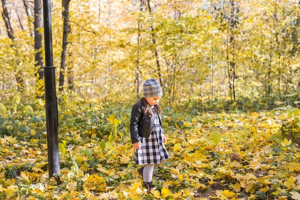Παιδιά, πτώση, αντίληψη - παιδί περπάτημα στο πάρκο φθινόπωρο και κρατώντας τα κίτρινα φύλλα τους ανθρώπους — Φωτογραφία Αρχείου