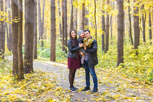 Familia, otoño, concepto de personas - familia joven de raza mixta caminando en el parque en el día de otoño — Foto de Stock